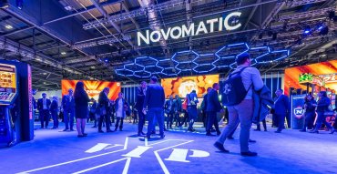 NOVOMATIC Messestand in blauem Design und Interessenten